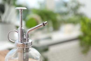 Photo of Houseplant care. Glass spray bottle indoors, closeup. Space for text