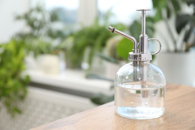 Photo of Houseplant care. Spray bottle on wooden table indoors, closeup. Space for text
