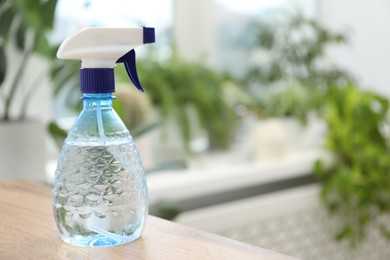 Photo of Houseplant care. Spray bottle on wooden table indoors, closeup. Space for text