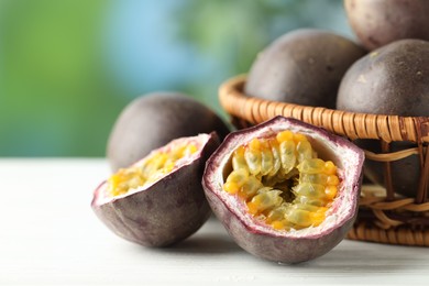 Photo of Fresh passion fruits in wicker basket on white wooden table outdoors, closeup