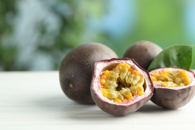 Photo of Fresh passion fruits on white wooden table outdoors, closeup. Space for text