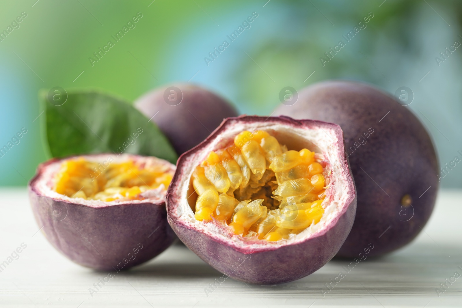 Photo of Fresh passion fruits on white wooden table outdoors, closeup