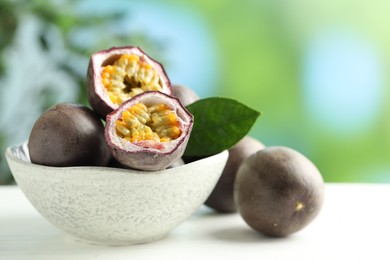 Photo of Fresh passion fruits in bowl on white wooden table outdoors, closeup