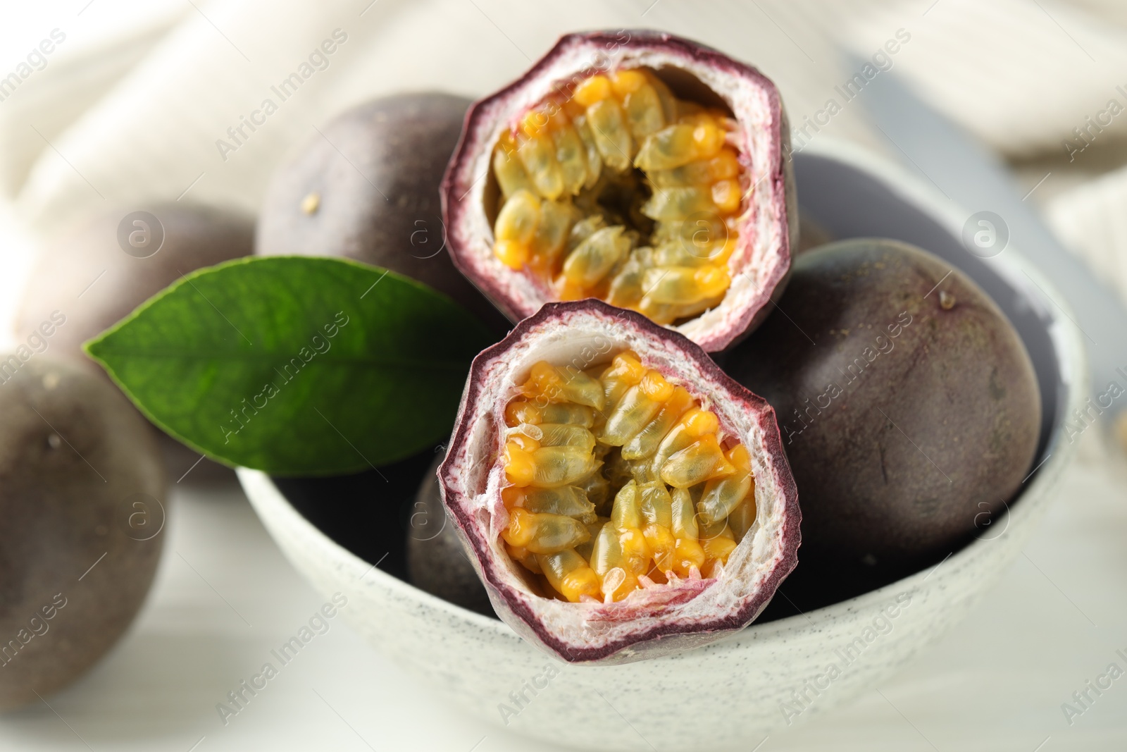 Fresh passion fruits in bowl on white table, closeup Photo of Fresh passion fruits in bowl on white table, closeup