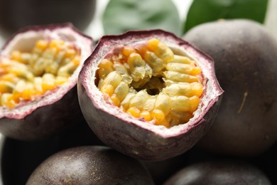 Photo of Fresh passion fruits and green leaves as background, closeup
