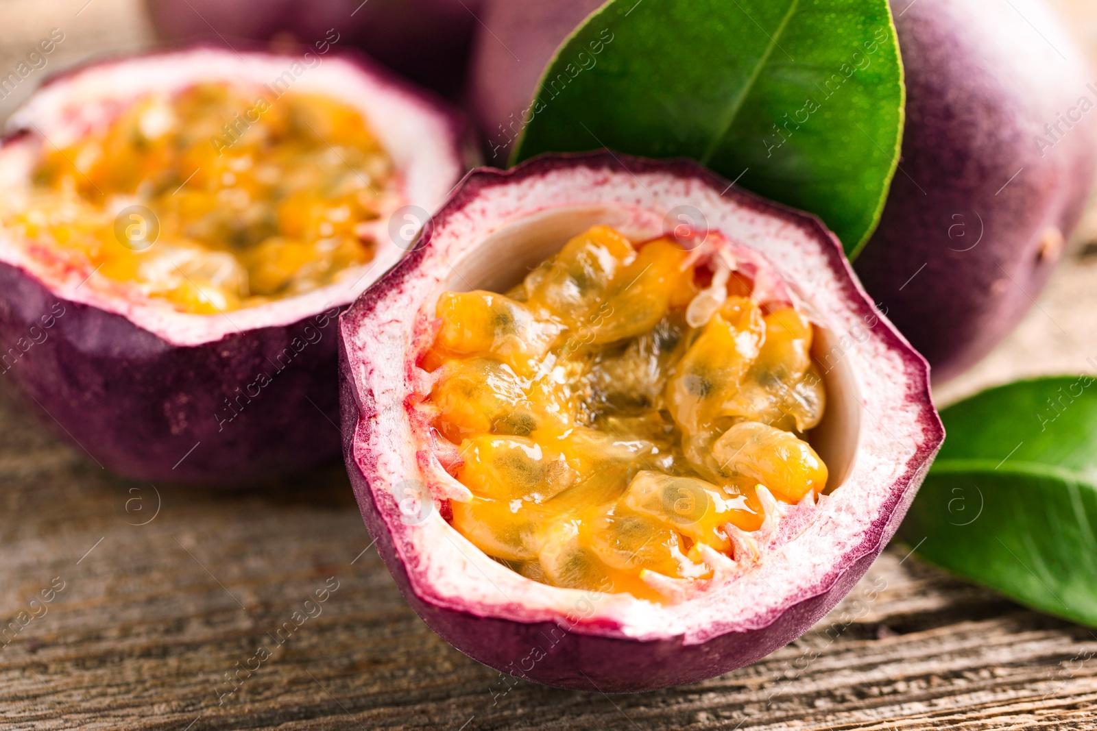 Fresh passion fruits and green leaves on wooden table, closeup Photo of Fresh passion fruits and green leaves on wooden table, closeup