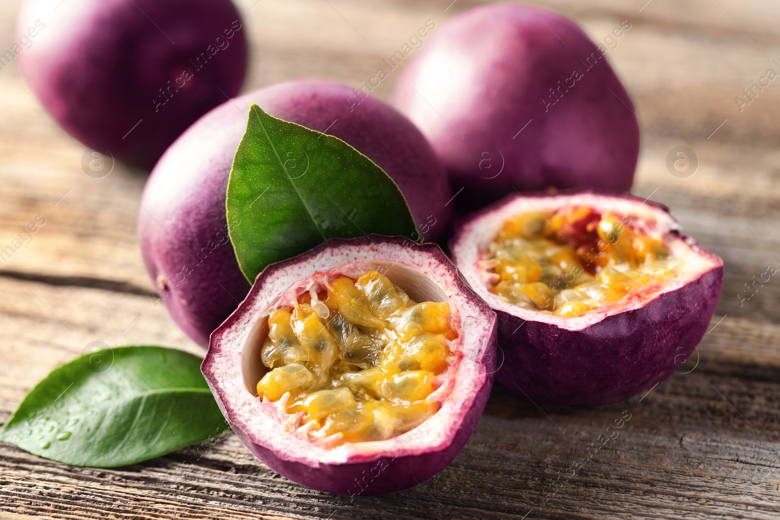 Fresh passion fruits and green leaves on wooden table, closeup Photo of Fresh passion fruits and green leaves on wooden table, closeup