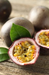 Photo of Fresh passion fruits and green leaves on wooden table, closeup