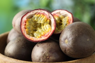 Photo of Fresh passion fruits in bowl outdoors, closeup