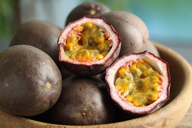 Photo of Fresh passion fruits in bowl outdoors, closeup