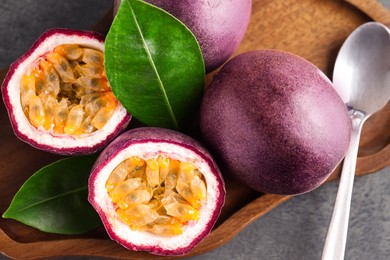 Photo of Fresh passion fruits and green leaves on grey table, top view