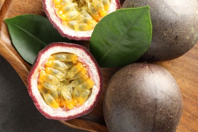 Photo of Fresh passion fruits and green leaves on grey table, top view