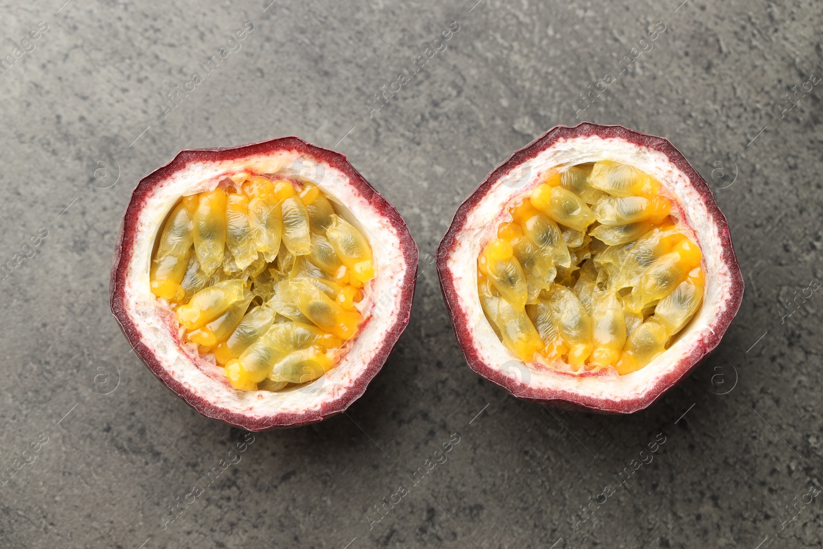 Halves of fresh passion fruit on grey table, flat lay Photo of Halves of fresh passion fruit on grey table, flat lay