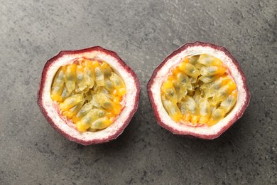 Photo of Halves of fresh passion fruit on grey table, flat lay