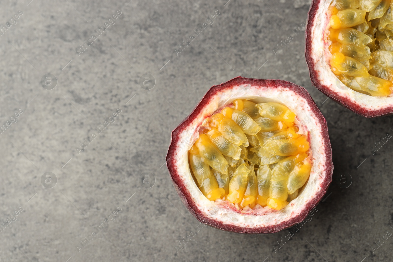 Halves of fresh passion fruit on grey table, flat lay. Space for text Photo of Halves of fresh passion fruit on grey table, flat lay. Space for text