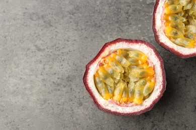 Photo of Halves of fresh passion fruit on grey table, flat lay. Space for text