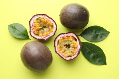 Photo of Fresh passion fruits and leaves on pale green background, flat lay