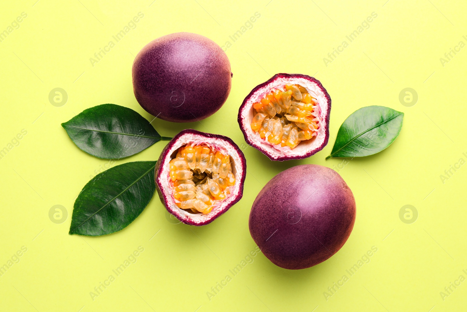 Fresh passion fruits and leaves on pale green background, flat lay Photo of Fresh passion fruits and leaves on pale green background, flat lay