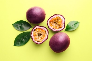 Photo of Fresh passion fruits and leaves on pale green background, flat lay
