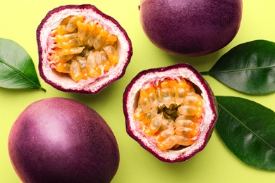 Photo of Fresh passion fruits and leaves on pale green background, flat lay