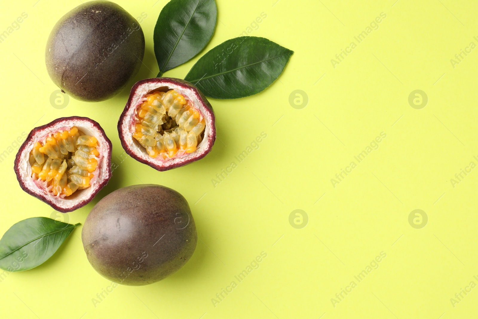 Fresh passion fruits and leaves on pale green background, flat lay. Space for text Photo of Fresh passion fruits and leaves on pale green background, flat lay. Space for text