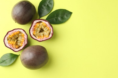Photo of Fresh passion fruits and leaves on pale green background, flat lay. Space for text