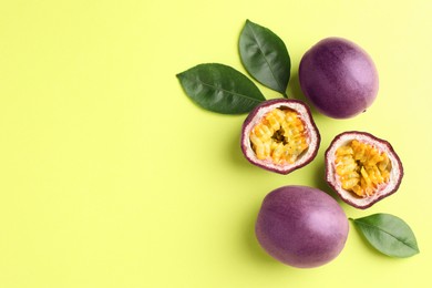 Photo of Fresh passion fruits and leaves on pale green background, flat lay. Space for text