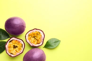 Photo of Fresh passion fruits and leaves on pale green background, flat lay. Space for text