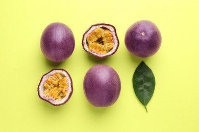 Photo of Fresh passion fruits and leaf on pale green background, flat lay