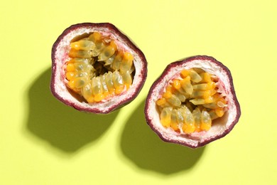 Photo of Halves of fresh passion fruit on pale green background, flat lay