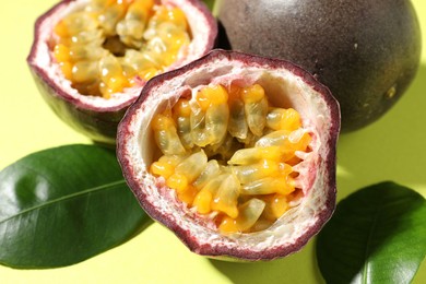Photo of Fresh passion fruits and leaves on pale green background, closeup
