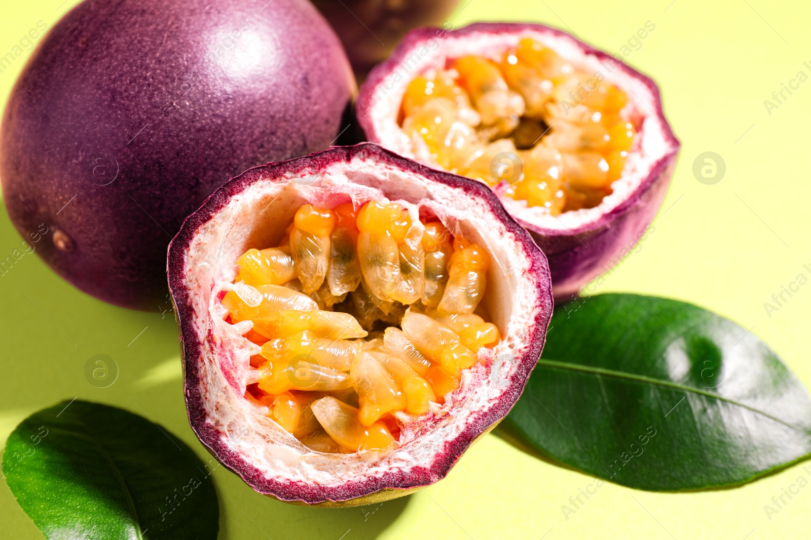 Fresh passion fruits and leaves on pale green background, closeup Photo of Fresh passion fruits and leaves on pale green background, closeup