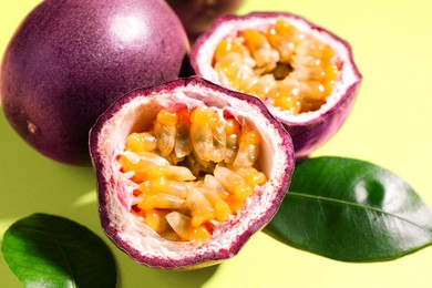 Photo of Fresh passion fruits and leaves on pale green background, closeup