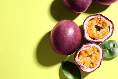 Photo of Fresh passion fruits and leaves on pale green background, flat lay. Space for text