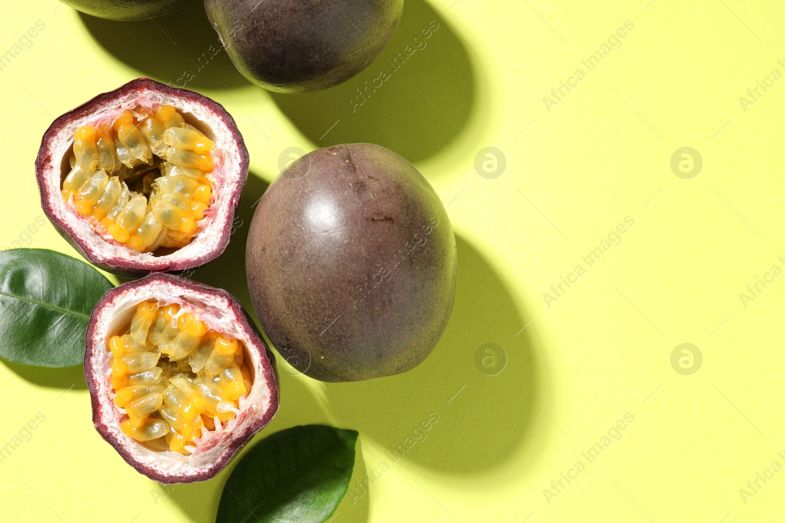Fresh passion fruits and leaves on pale green background, flat lay. Space for text Photo of Fresh passion fruits and leaves on pale green background, flat lay. Space for text