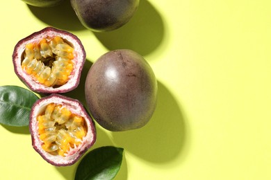 Photo of Fresh passion fruits and leaves on pale green background, flat lay. Space for text