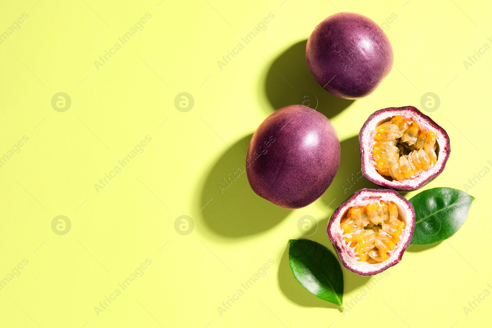 Fresh passion fruits and leaves on pale green background, flat lay. Space for text Photo of Fresh passion fruits and leaves on pale green background, flat lay. Space for text