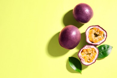 Photo of Fresh passion fruits and leaves on pale green background, flat lay. Space for text