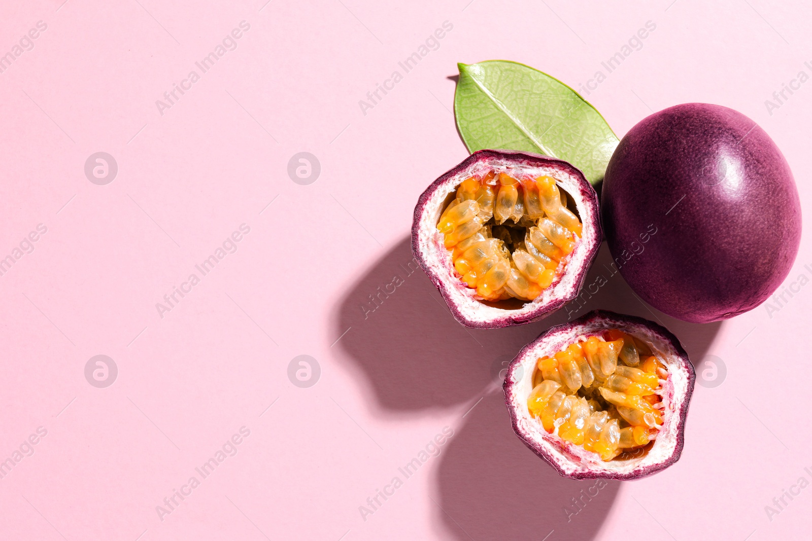 Fresh passion fruits and green leaf on pink background, flat lay. Space for text Photo of Fresh passion fruits and green leaf on pink background, flat lay. Space for text
