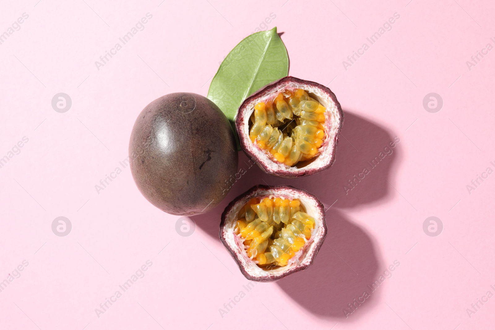 Fresh passion fruits and green leaf on pink background, flat lay Photo of Fresh passion fruits and green leaf on pink background, flat lay
