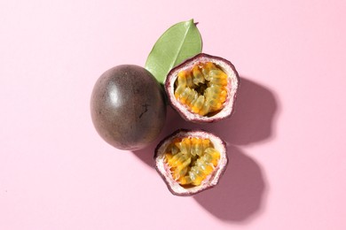 Photo of Fresh passion fruits and green leaf on pink background, flat lay