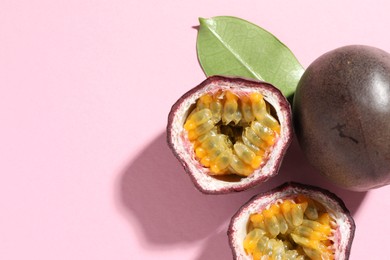 Photo of Fresh passion fruits and green leaf on pink background, flat lay. Space for text