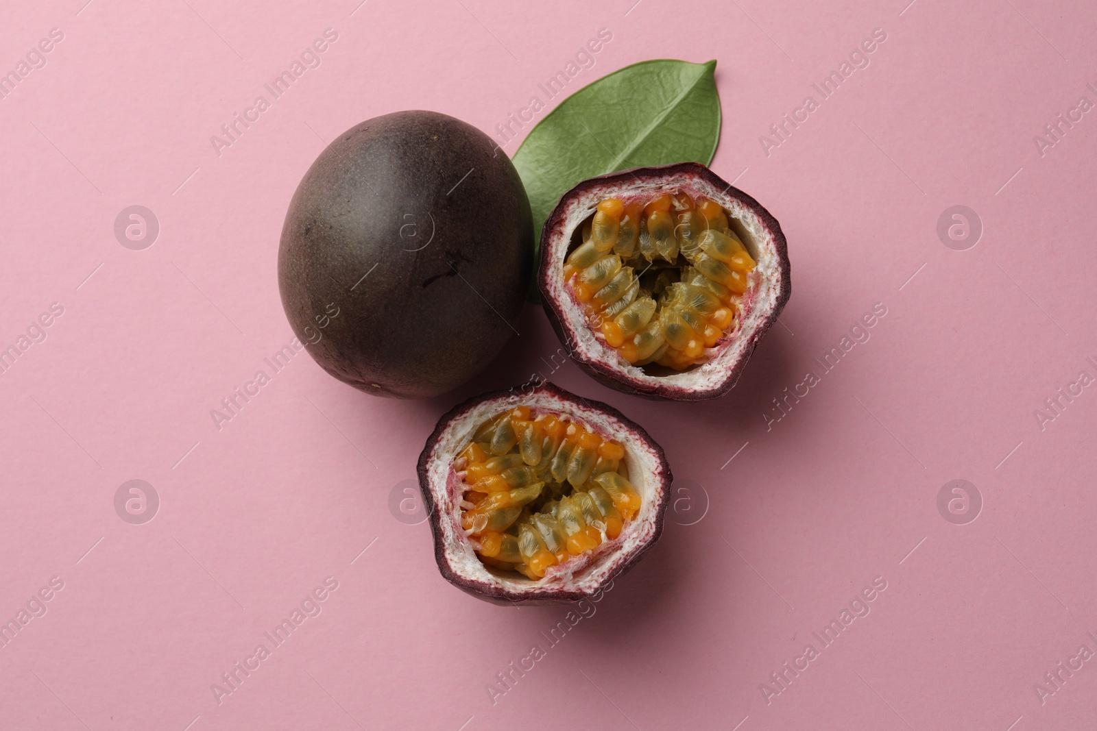 Fresh passion fruits and green leaf on pink background, flat lay Photo of Fresh passion fruits and green leaf on pink background, flat lay