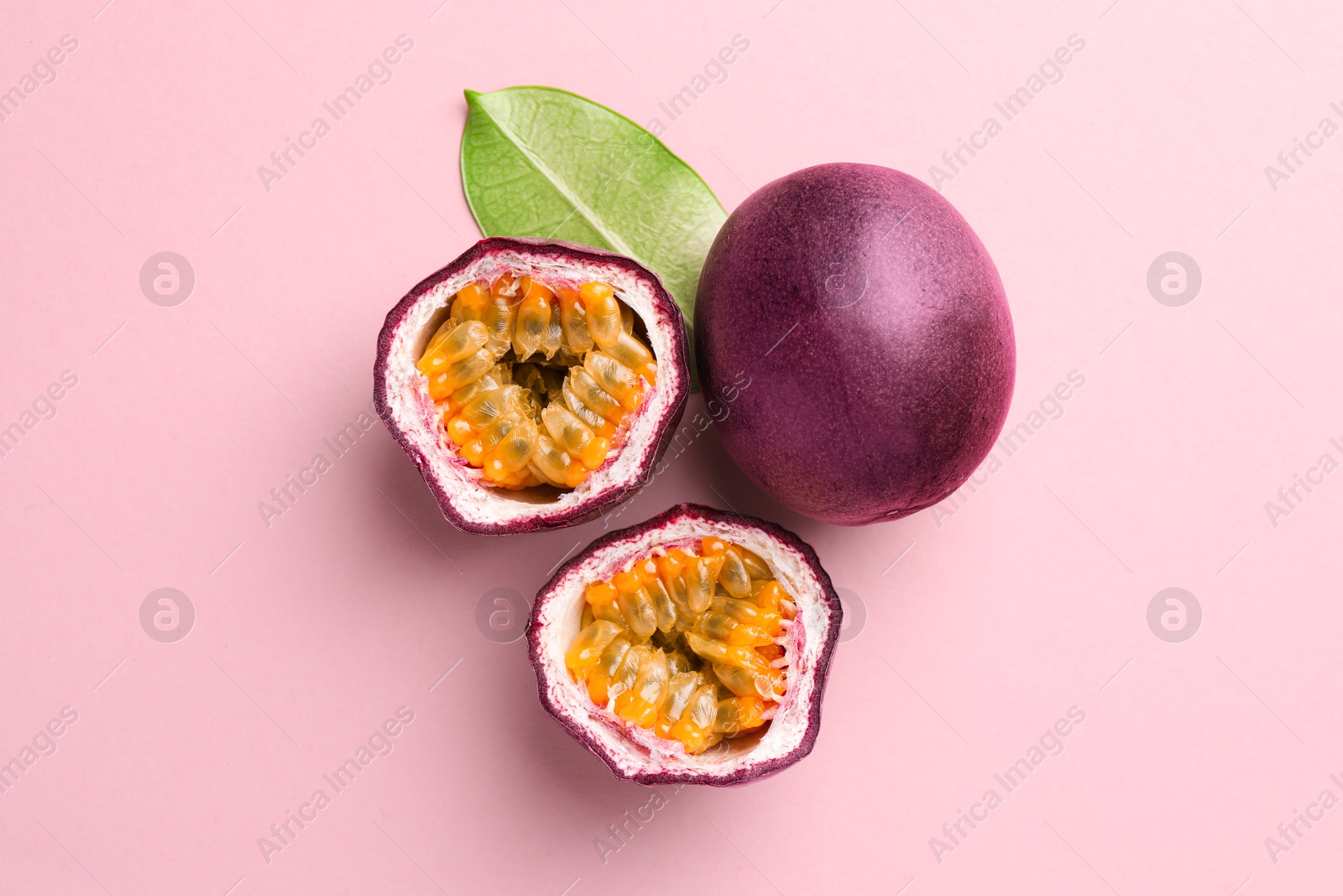 Fresh passion fruits and green leaf on pink background, flat lay Photo of Fresh passion fruits and green leaf on pink background, flat lay