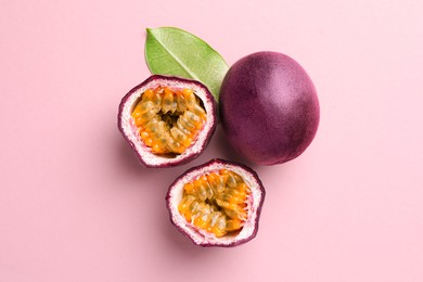 Photo of Fresh passion fruits and green leaf on pink background, flat lay