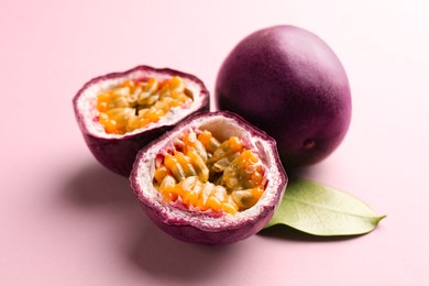 Photo of Fresh passion fruits and green leaf on pink background, closeup
