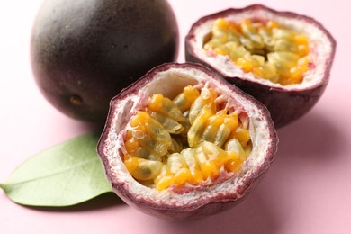 Photo of Fresh passion fruits and green leaf on pink background, closeup