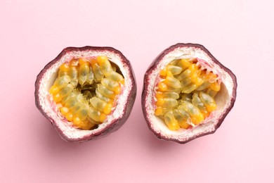 Photo of Halves of fresh passion fruit on pink background, flat lay
