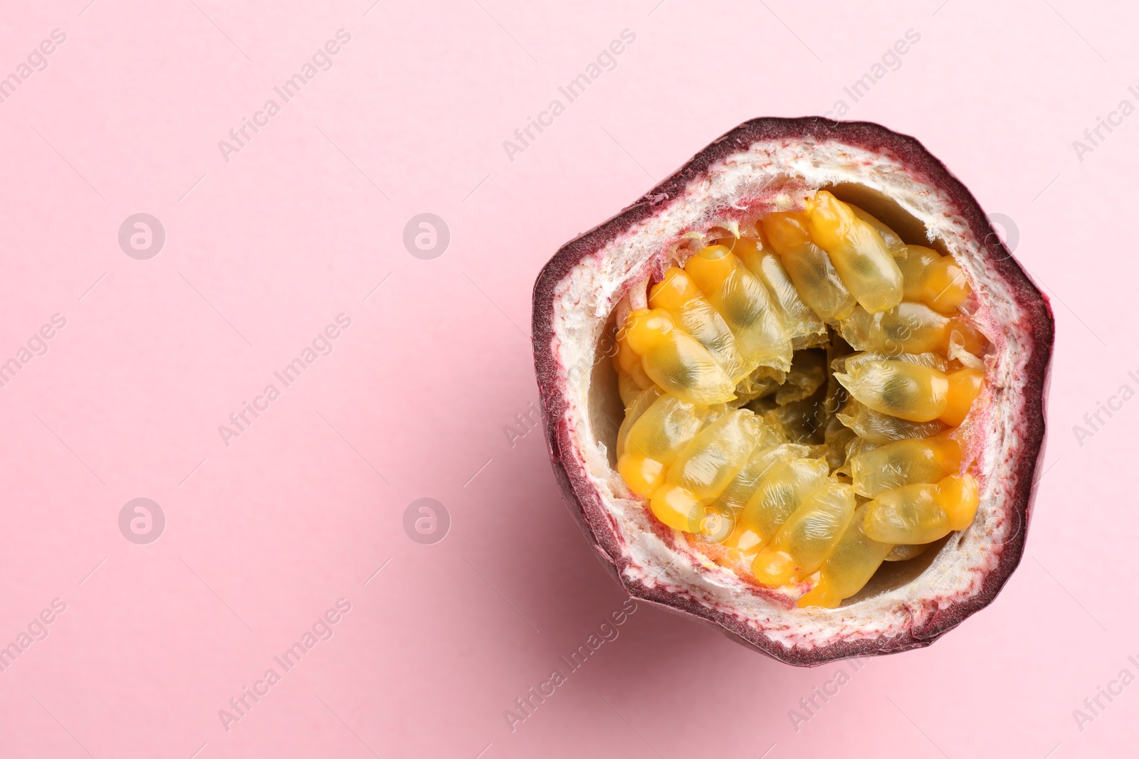 Half of fresh passion fruit on pink background, top view. Space for text Photo of Half of fresh passion fruit on pink background, top view. Space for text