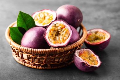 Photo of Fresh passion fruits in wicker basket on grey table, closeup